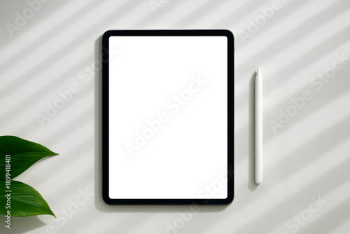 Tablet mockup with digital pen on bright desk in soft daylight with plant shadows