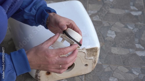 Replacing the sealing gasket of the toilet flush tank, A plumber replaces the rubber gasket that connects the tank with the toilet bowl