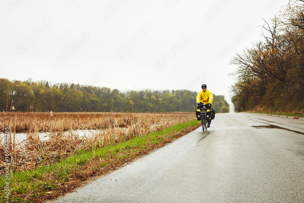 Obraz premium Man, helmet and bicycle outdoor for fitness, exercise and minimalistic travel. Space, mature cyclist and cycling for bikepacking trip, workout safety and rain weather for tourism adventure in nature