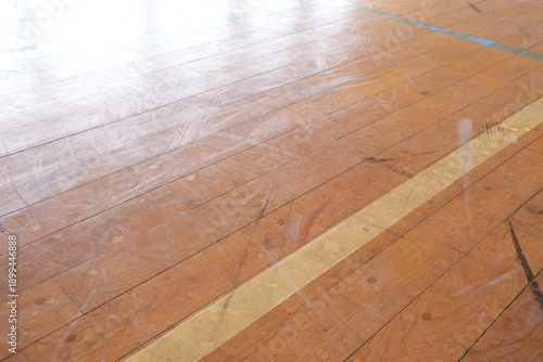A wooden floor with a white line down the middle. The floor is dirty and has a lot of scuff marks