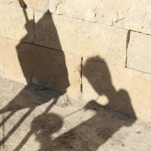 The shadows are dark gray, contrasting against the light beige wall and ground. The position of the objects, suggested by the shadow,