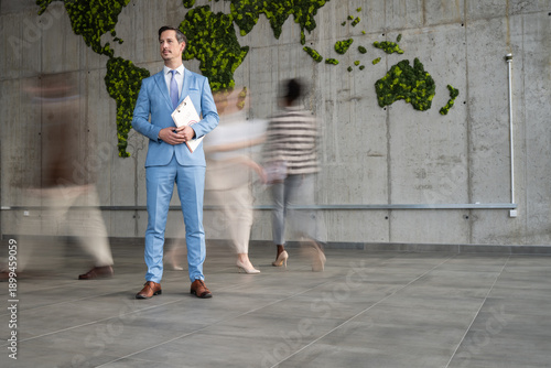 Tablou pe pânză Businessman standing while people moving in busy corporate office