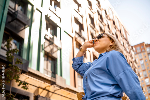 Quadro su tela Smiling woman property investor standing near high rise apartment complex on sun