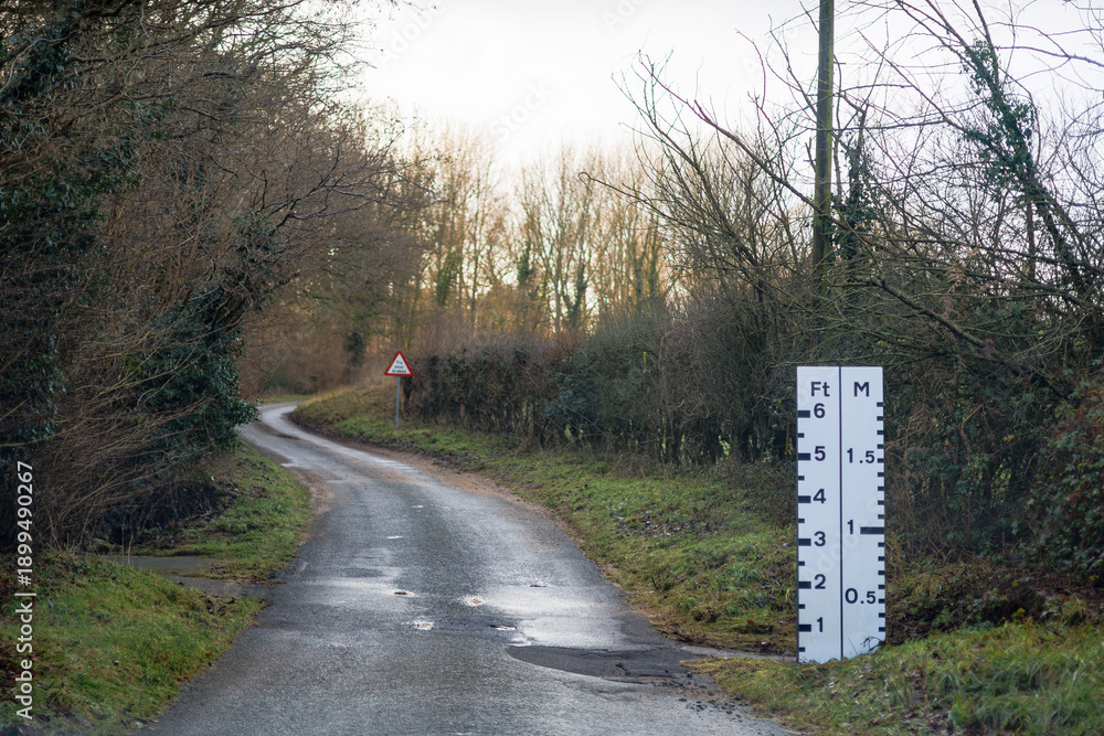 Naklejka premium winding countryside road with flood marking warning