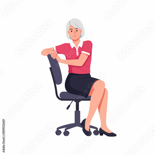 An older woman with short grey hair sits backwards on an office chair, smiling, wearing a pink polo shirt and a dark skirt.