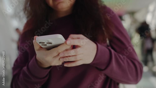 Close up of caucasian woman hands holding smartphone indoors with modern interior background, focused on mobile use, representing technology and everyday digital communication.