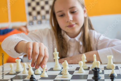 Hand of school girl moving a chess piece on chessboard