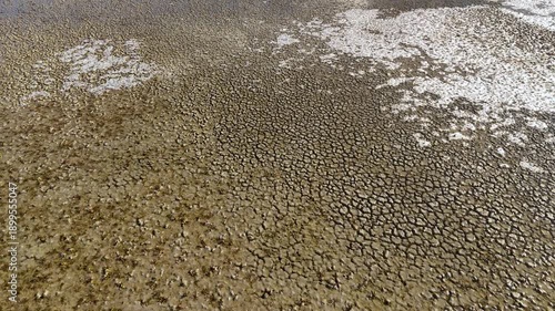 Texture detail of dried and cracked mud at the edge of a lake during winter showing a pattern of drought in a remote natural setting