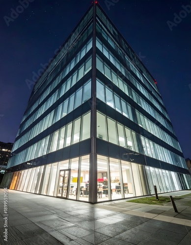 Modern, angular office building at night with lit windows