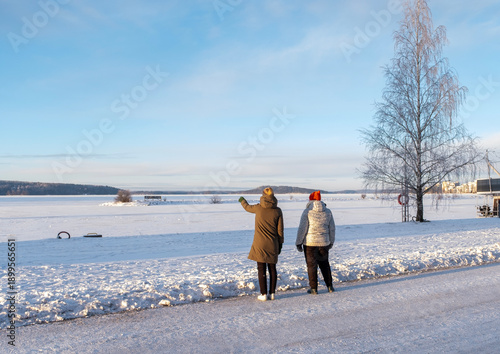 Woman with a teenager on a winter walk, city embankment.