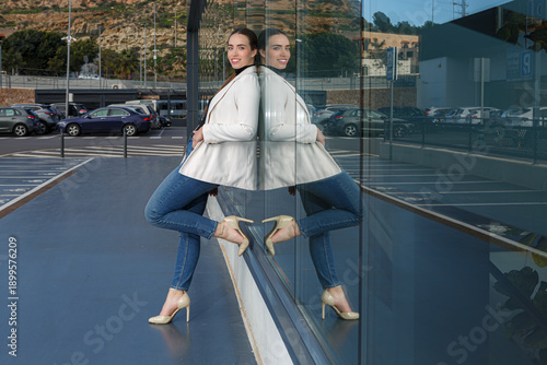 Woman posing near reflective glass surface at outdoor shopping center