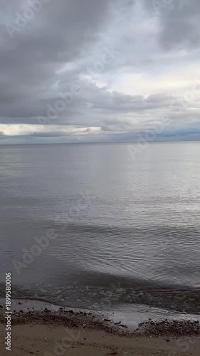 The seashore in cloudy weather, calm water, calm water in the evening. Weather before rain