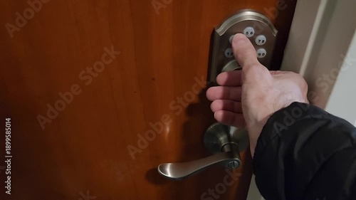 Male hand entering code on keypad lock of entrance door