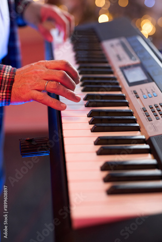 A close-up of hands playing a digital keyboard synthesizer
