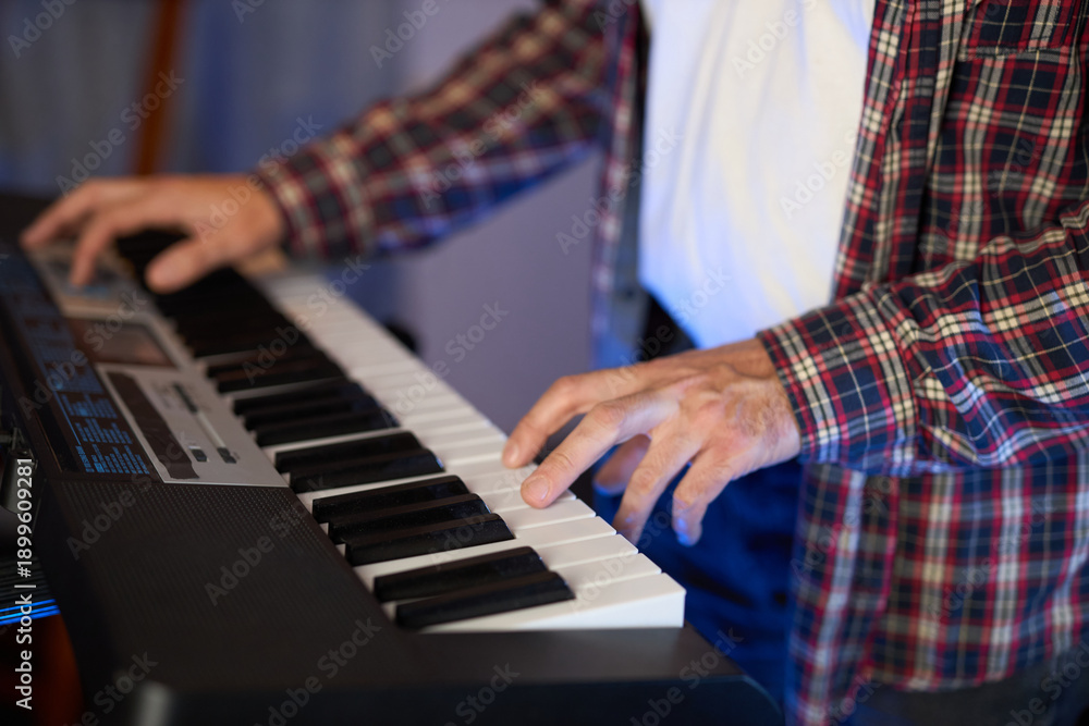 Obraz premium A close-up of hands playing a digital keyboard synthesizer