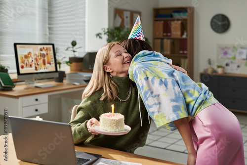 Billede på lærred Adult woman smiling while receiving hug from young woman wearing party hat, hold