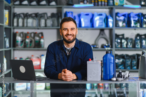 Tableau sur toile Smiling auto parts store salesman working at desk
