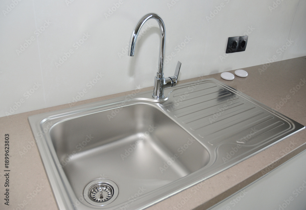 Fototapeta premium Kitchen countertop with a metallic kitchen sink and stainless steel faucet