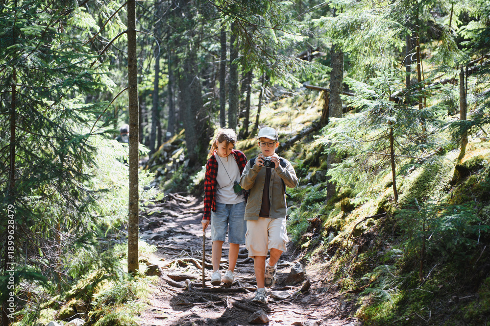 Obraz premium Tourists hiking in forest, children exploring nature with camera