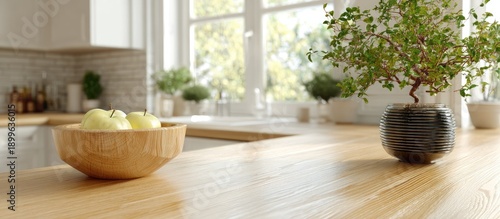 Wooden Bowl of Green Apples and Decorative Plant on Light Wood Counter in Sunny Kitchen