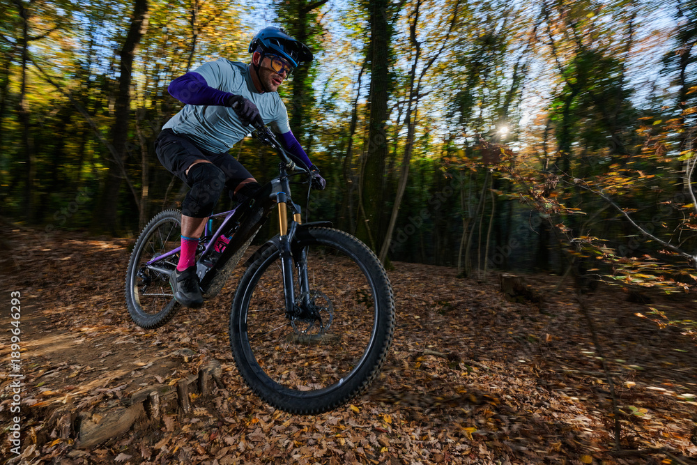 Naklejka premium Mountain Biker Racing Through Autumn Forest Trail – Action Shot On a Leafy Trail