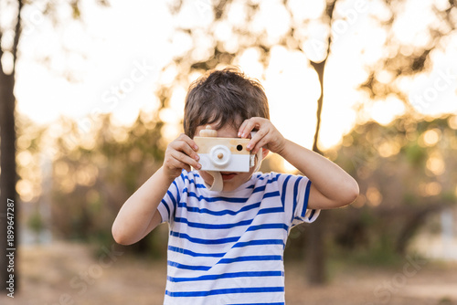 Bilde på lerret Child holding wood camera toy playing outdoors