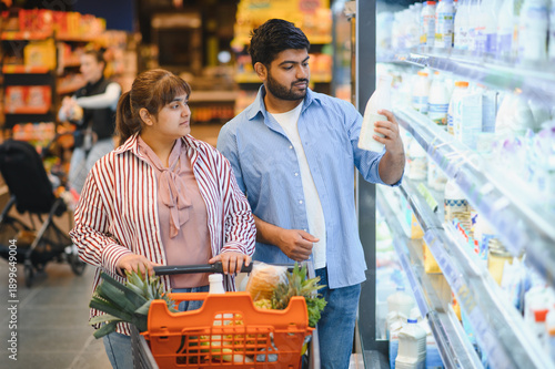 Photos Indian couple choosing milk in grocery store refrigerator