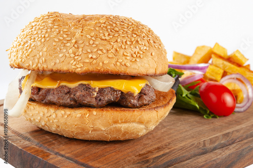 Hamburger with potatoes and vegetables on a wooden board