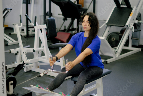 Woman doing seated back exercise on machine in gym