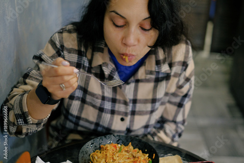 Woman eating Asian noodles with fork