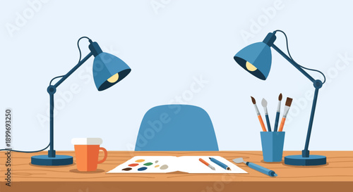 Artist's workspace with two lamps, a cup, and art supplies