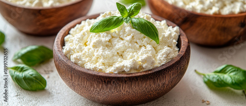 Fresh cottage cheese sits in a wooden bowl with greens — the perfect atmospheric backdrop for food blogs or healthy eating advertisements.