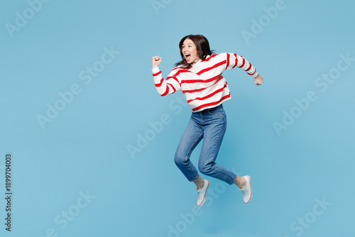 Canvas-taulu Full body side view young shocked surprised woman she wear red striped sweatshirt casual clothes jump high run fast isolated on plain pastel light blue background studio portrait