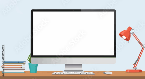 A desktop computer setup with books, a plant, and a desk lamp on a wooden surface