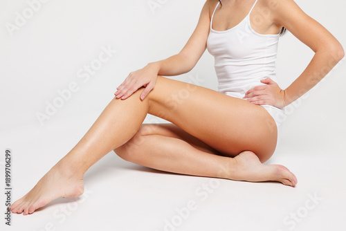 Closeup cropped side view young woman with slim body perfect skin wear lingerie underwear sit with long legs extended isolated on plain solid white background studio portrait. Lifestyle diet concept.