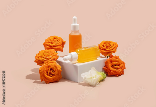 two cosmetic bottles with  a dropper on a white podium surrounded by blooming roses. The concept of natural cosmetics, natural essential oils and skin care products