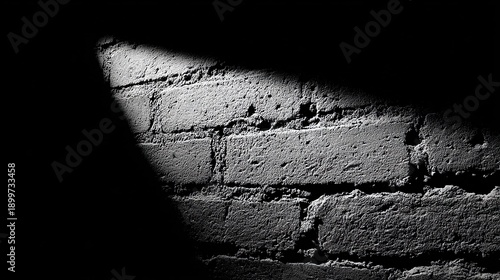 Close-up monochrome of a brick wall illuminated by a stark diagonal light beam