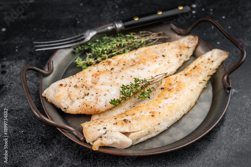 Fotografía Roasted flaky whitefish fillets with fresh thyme, overhead food photo on moody dark background with copy space