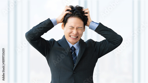 強いストレスに耐えきれず頭を抱えるビジネスマン, Overwhelmed businessman clutching his head under stress