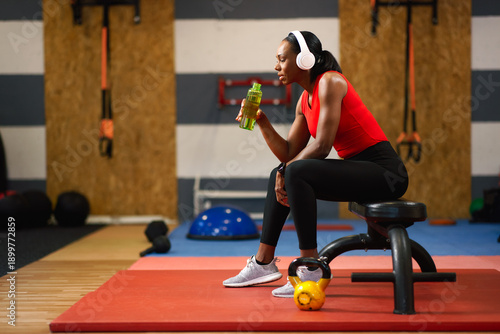 Female athlete taking a break and hydrating in gym
