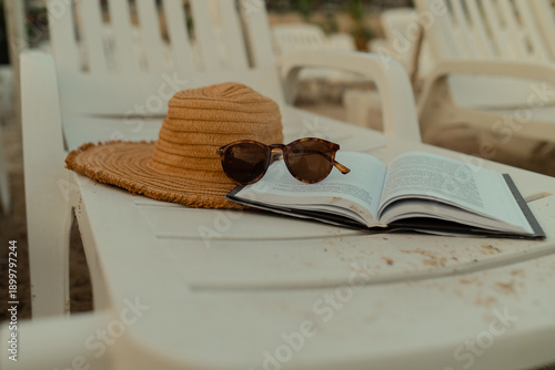 Schilderij op canvas Open book, straw hat and sunglasses on a white beach chair