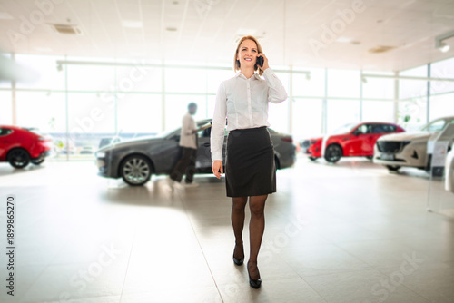 Wallpaper Mural Businesswoman talking on phone walking in car dealership showroom Torontodigital.ca