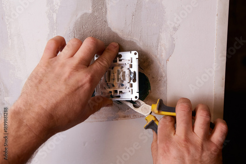 Photos An electrician uses pliers to cut electrical wire while working on installing a