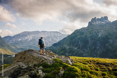 Man hiker looking at mountain peak in Styria, Austria. Epic alpine landscape with backpacker hiking during sunset in Alps mountains