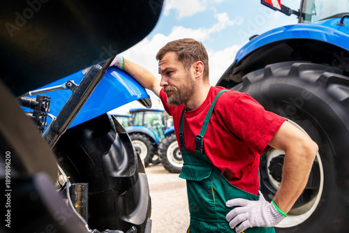 Quadro su tela Professional mechanic inspecting farm equipment outdoors.