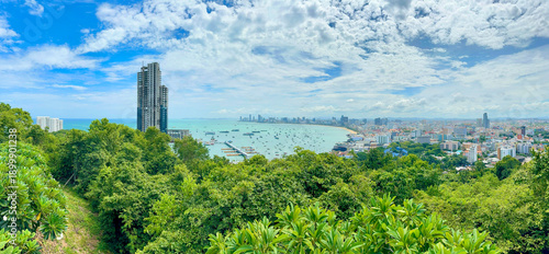 Fotografía Stunning coastal landscape of Pattaya bay featuring an abandoned skyscraper and lush green forest on the foreground