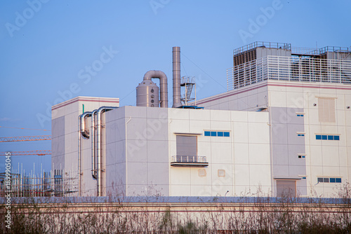 Exterior view of a large pharmaceutical or high-tech manufacturing plant in an industrial zone.Construction site of a contemporary industrial warehouse with advanced HVAC systems on the roof.