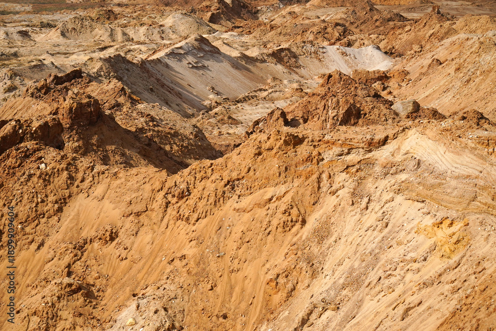 Obraz premium Expansive sandy landscape showcasing rugged terrain with varying elevations, highlighting natural erosion patterns and textures in a serene outdoor environment