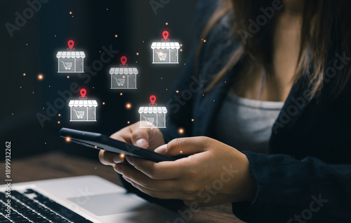 Slika na platnu Businesswoman using smartphone with multiple store icons and location pins, representing omnichannel retail, store location strategy, digital commerce expansion, and customer reach management