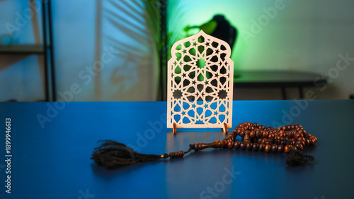 Islamic wood ornament with geometric pattern and prayer beads on blue desk, ramadan kareem and eid mubarak spiritual decoration with copy space